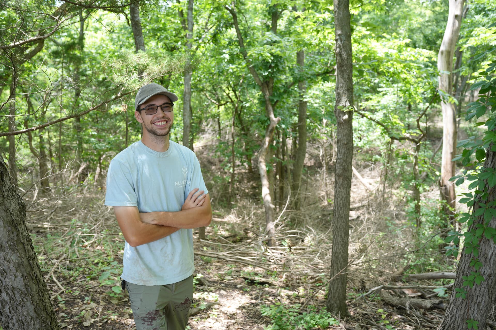 Andrew Gregorsok standing in a wooded area being cleared of brush