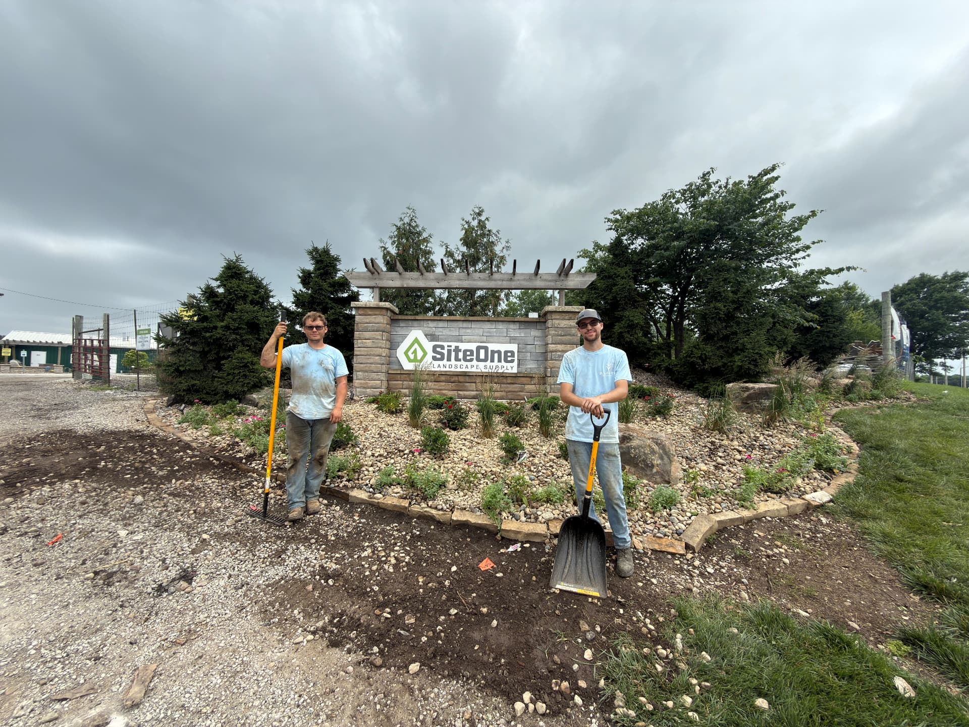 Colton Smith standing with a shovel at a finished landscape bed installation